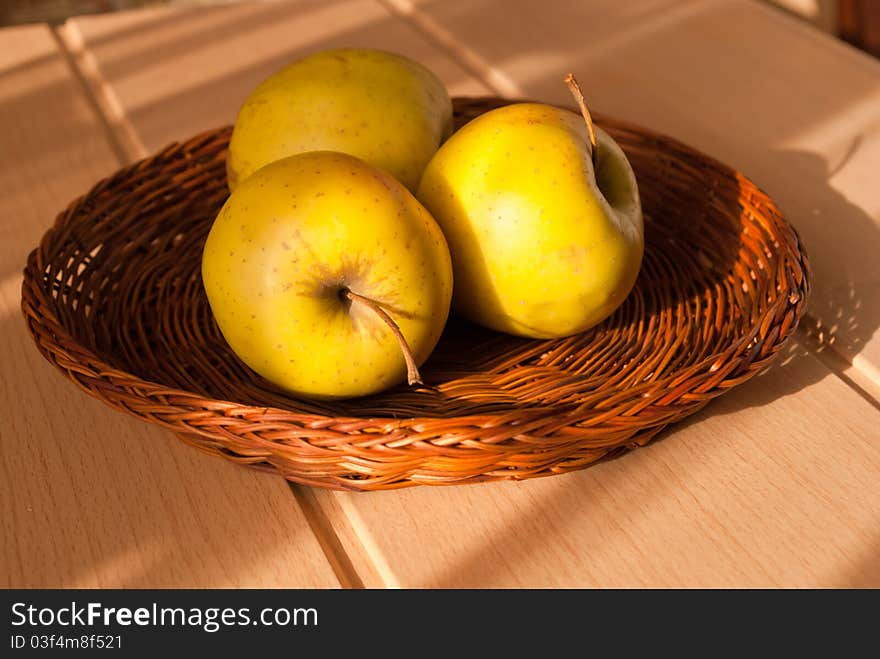 Three yellow apple in a straw dish. Three yellow apple in a straw dish.