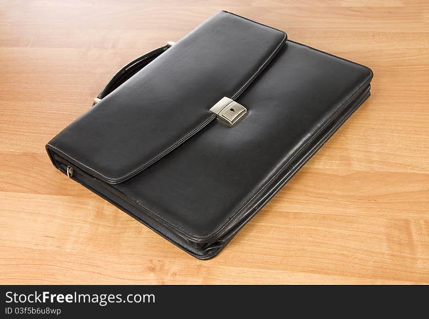 Fashionable leather briefcase on a  wooden table still life