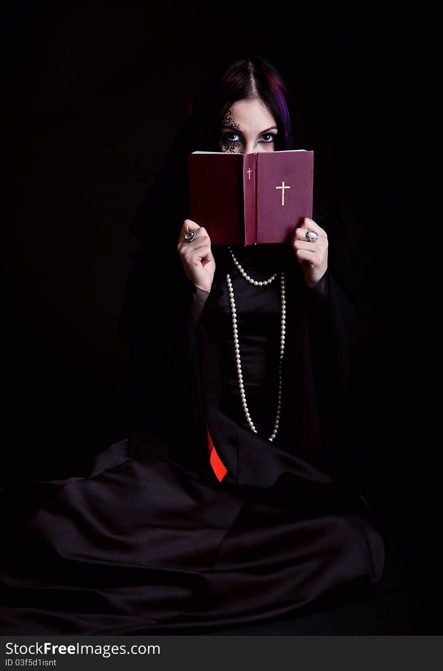 A gothic girl with the Bible. Isolated on a black bachground