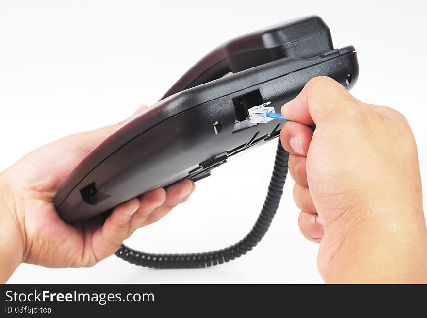 A hand plugin a telephone cable to the socket with isolated white background