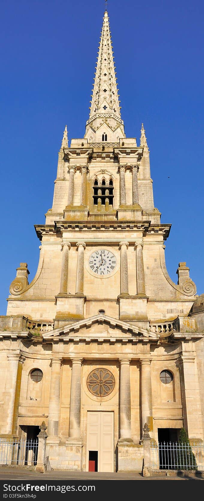 A French cathedral and its tall bell tower under a blue sky