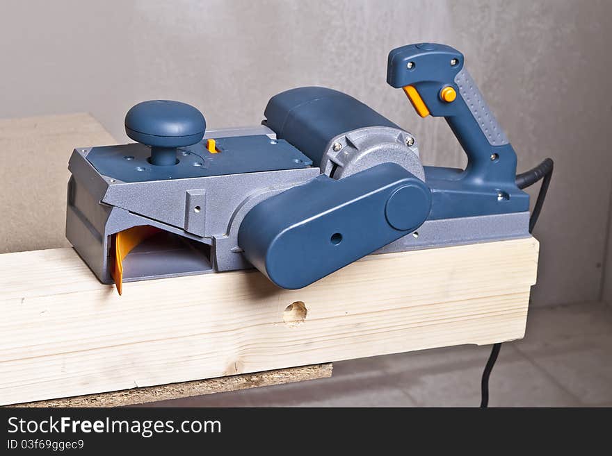 Close-up of a construction worker's hand and power tool while planing a piece of wood trim for a project. Close-up of a construction worker's hand and power tool while planing a piece of wood trim for a project.