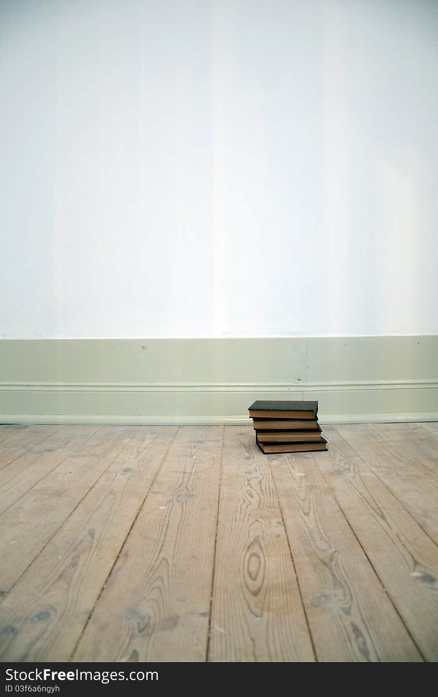 Old books or encyclopedia volumes lay down on the ground of empty living room. Old books or encyclopedia volumes lay down on the ground of empty living room