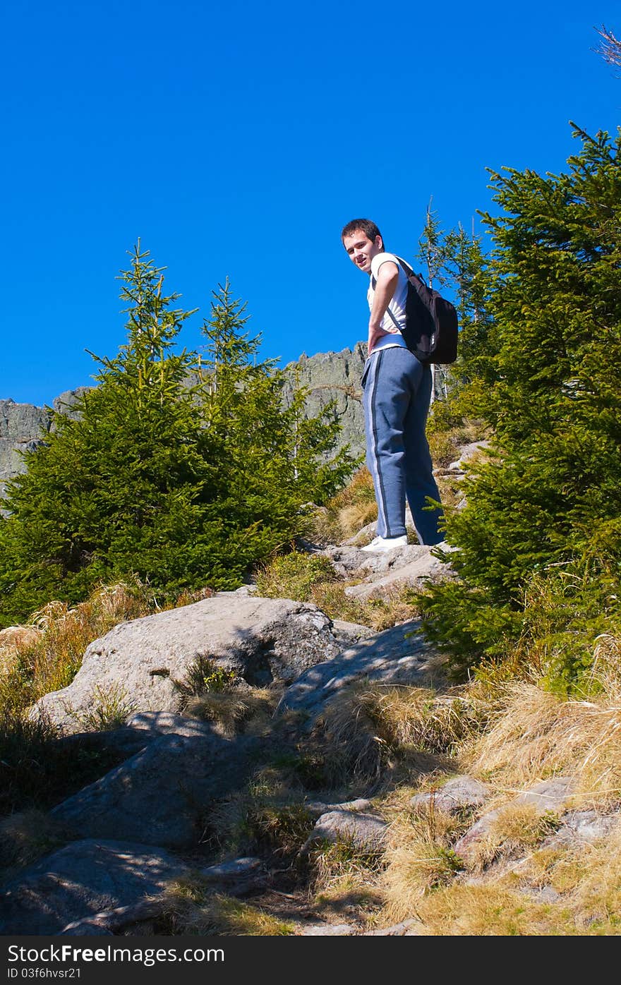 Man with backpack on a rocky path on the mountain looking behind. Man with backpack on a rocky path on the mountain looking behind.