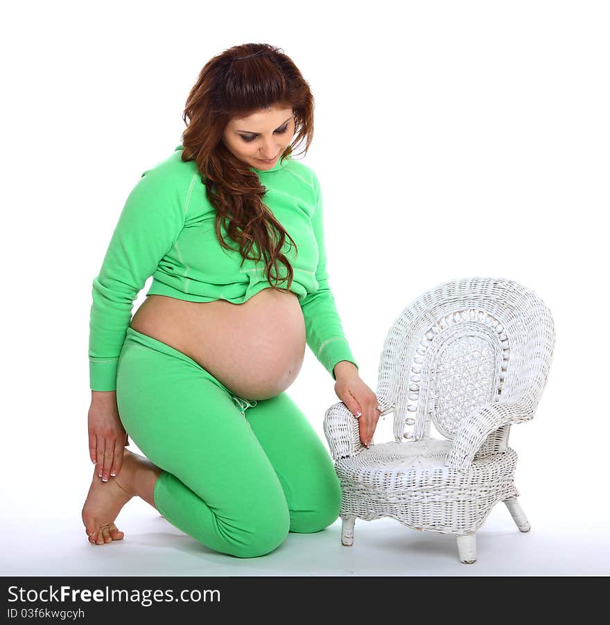 Pregnant woman kneeling next to a small white chair