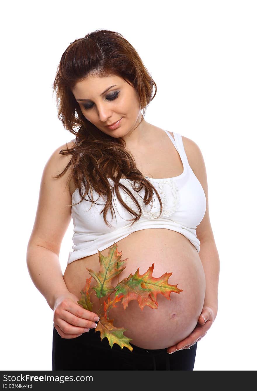 Pregnant woman holding a leaf next to her bare belly