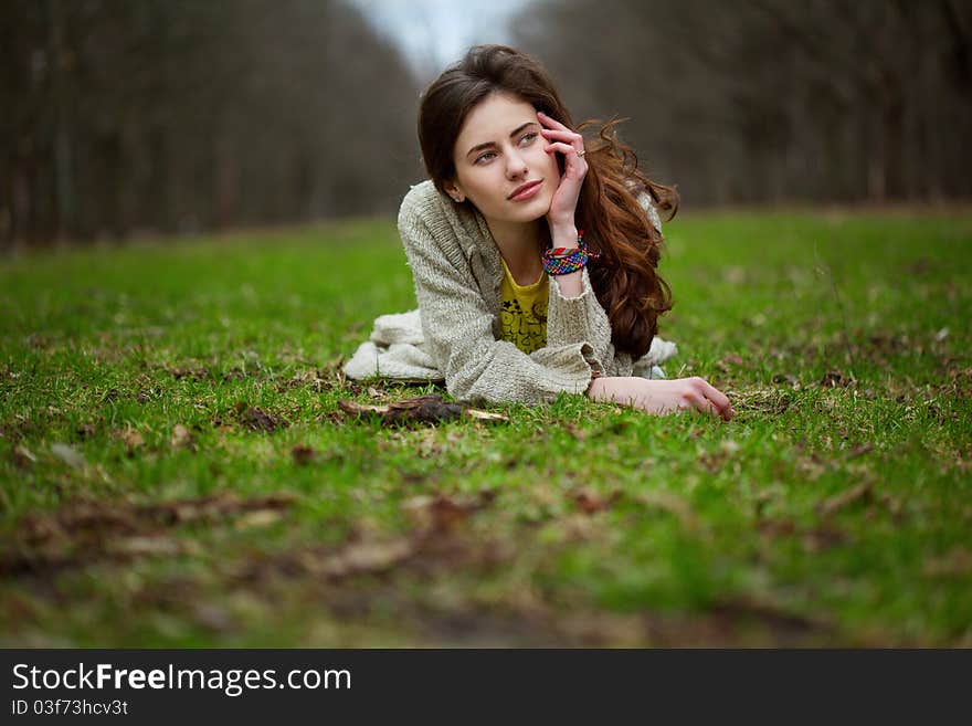 Young sweet girl lying in a grass and looking right