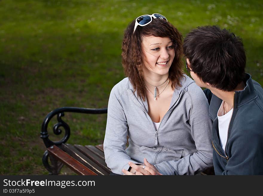 Attractive couple sitting on bench in the park