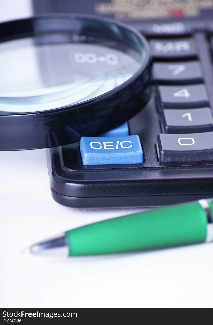 Ball pen, calculator and magnifying glass on white background