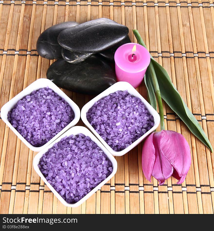 Lavender spa salt, spa stones, a candle and a tulip flower. Lavender spa salt, spa stones, a candle and a tulip flower