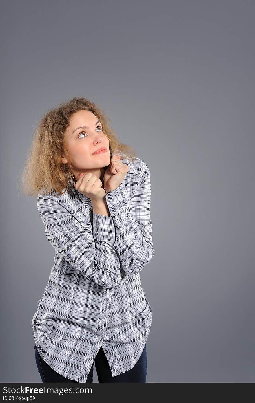 Portrait of a surprised young woman  looking upwards at copyspace against grey background