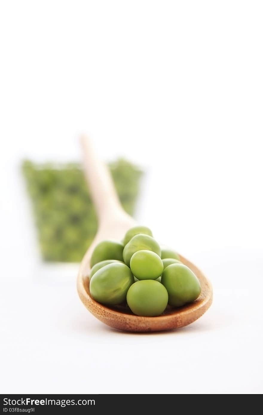 Fresh green pea on a small wooden spoon on white background with soft shadow