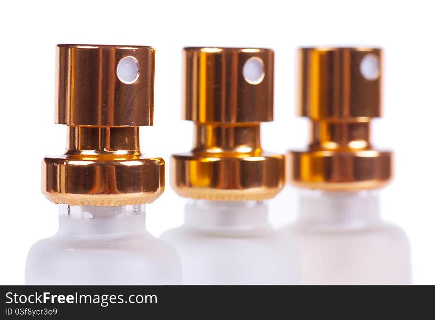 Sprayers of three perfume bottles isolated over white background. Macro view. Sprayers of three perfume bottles isolated over white background. Macro view.