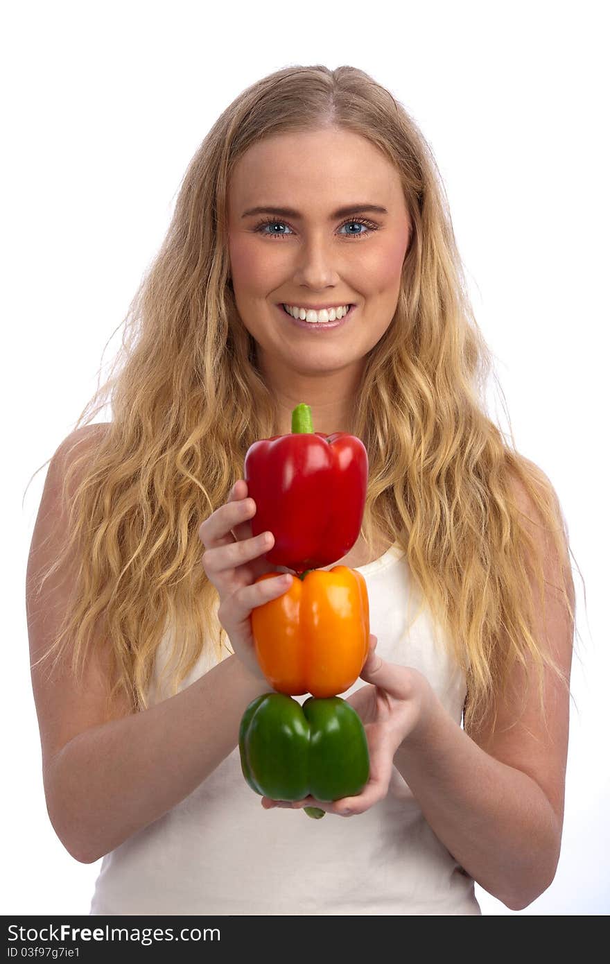 Beautiful blond caucasian young woman smiling and holding a traffic light of three bell peppers: red, orange, and green. Beautiful blond caucasian young woman smiling and holding a traffic light of three bell peppers: red, orange, and green