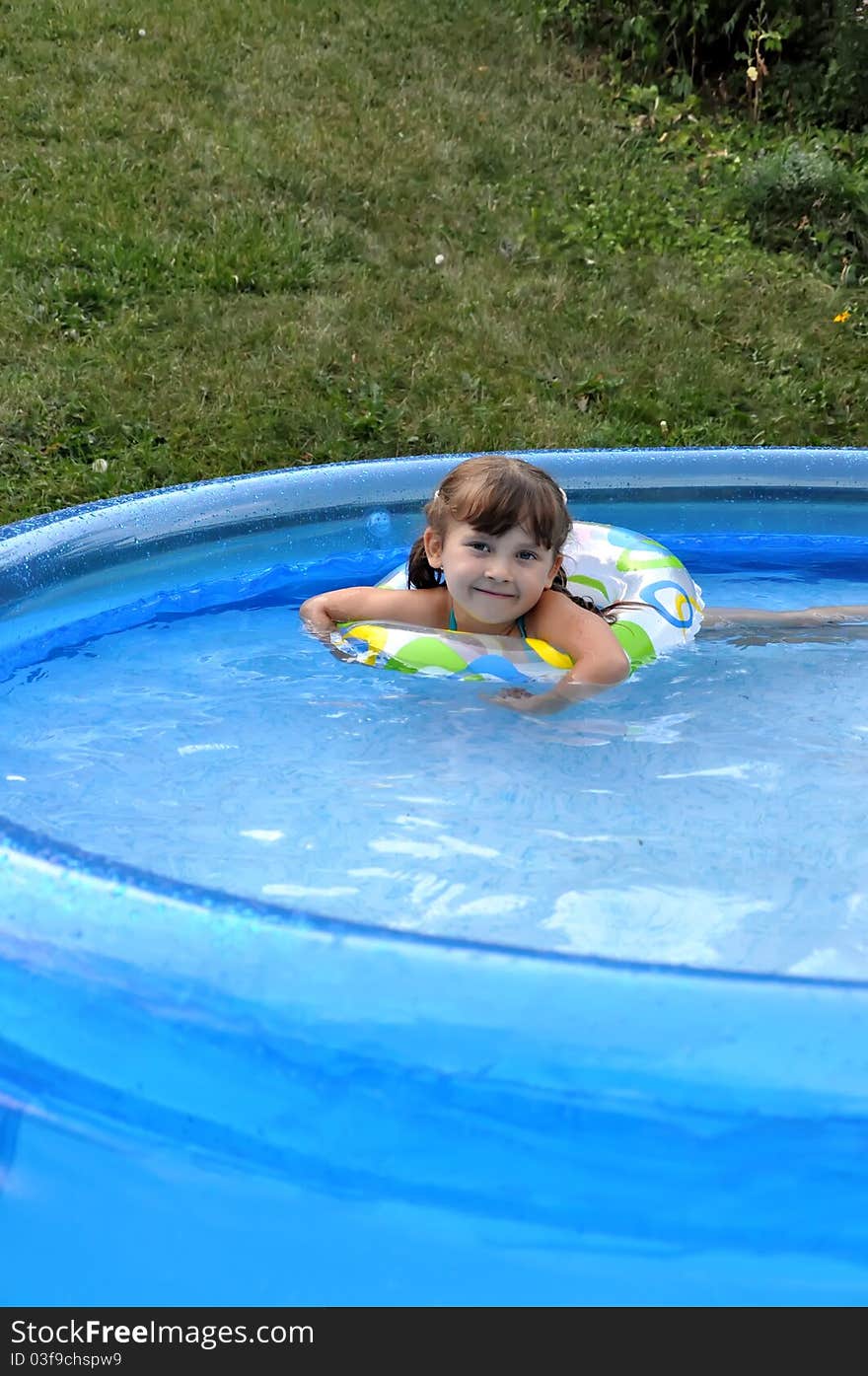 Little cute girl having fun swimming in a pool. Summer time, hot day. Little cute girl having fun swimming in a pool. Summer time, hot day.