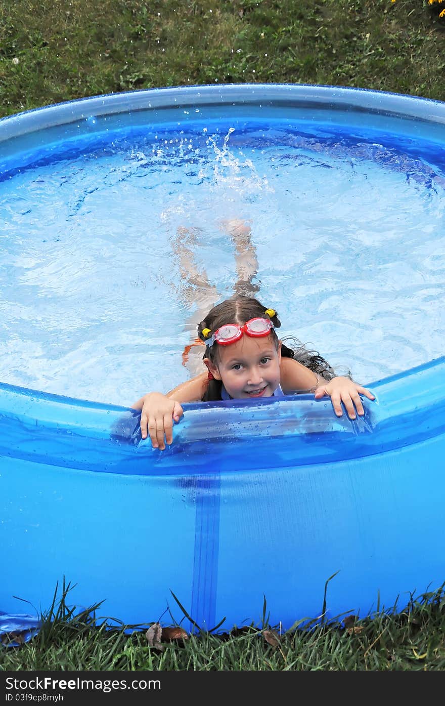 Little cute girl having fun swimming in a pool. Summer time, hot day. Little cute girl having fun swimming in a pool. Summer time, hot day.