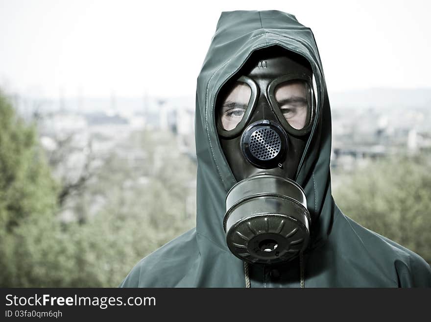 Man in gas mask on demolished industrial background with pipes