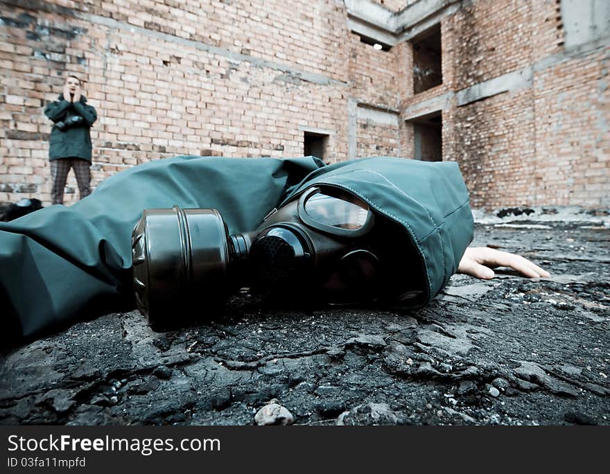 Man in gas mask fallen to the ground on demolished industrial background