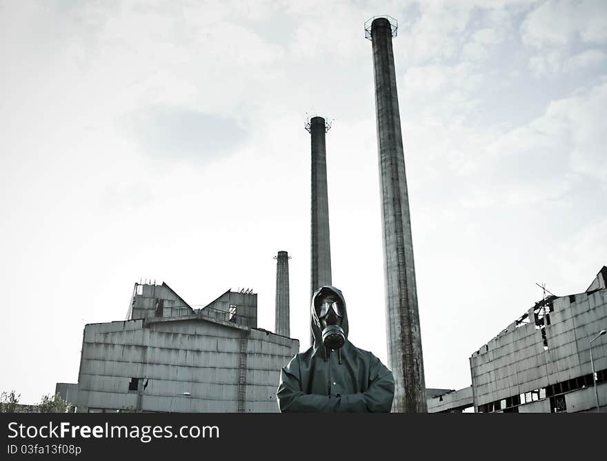 Man in gas mask on demolished industrial background with pipes