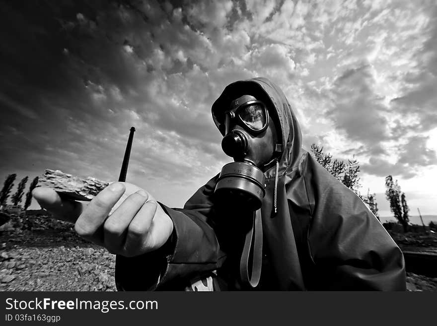 Scientist with gas mask examining rock in destroyed territory after explosion. Scientist with gas mask examining rock in destroyed territory after explosion