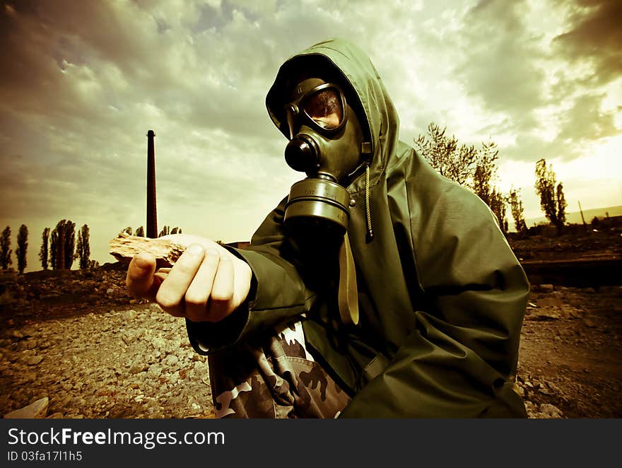 Scientist with gas mask examining rock in destroyed territory after explosion. Scientist with gas mask examining rock in destroyed territory after explosion