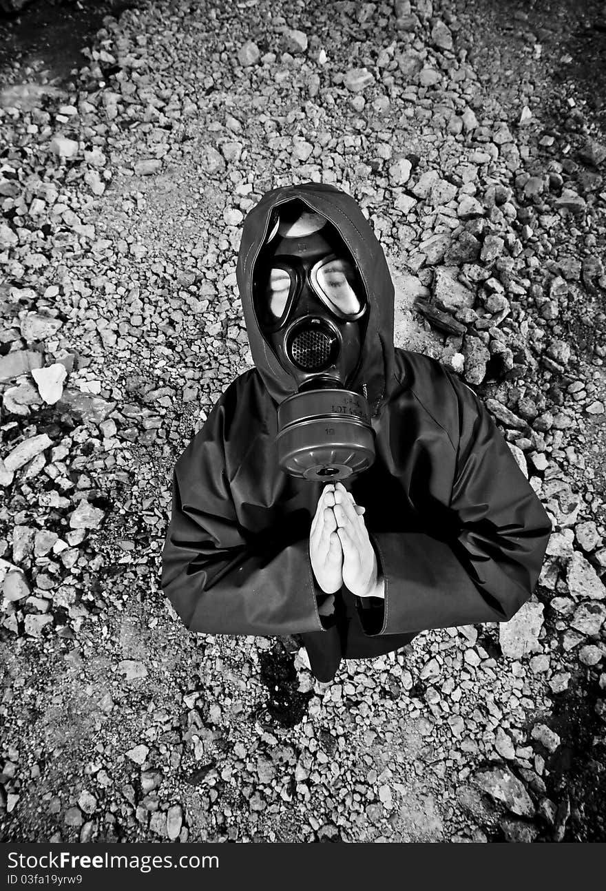 Scientist with gas mask praying in destroyed territory after explosion. Scientist with gas mask praying in destroyed territory after explosion