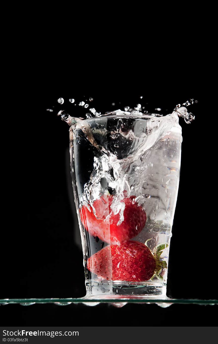 Two strawberries put in a glass full of water. Two strawberries put in a glass full of water