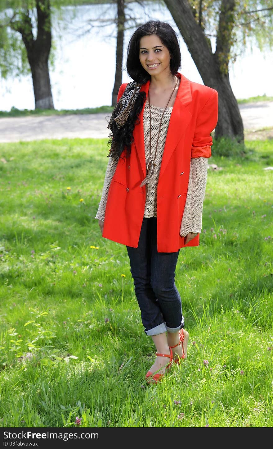 Beautiful brunette girl in red coat at the park