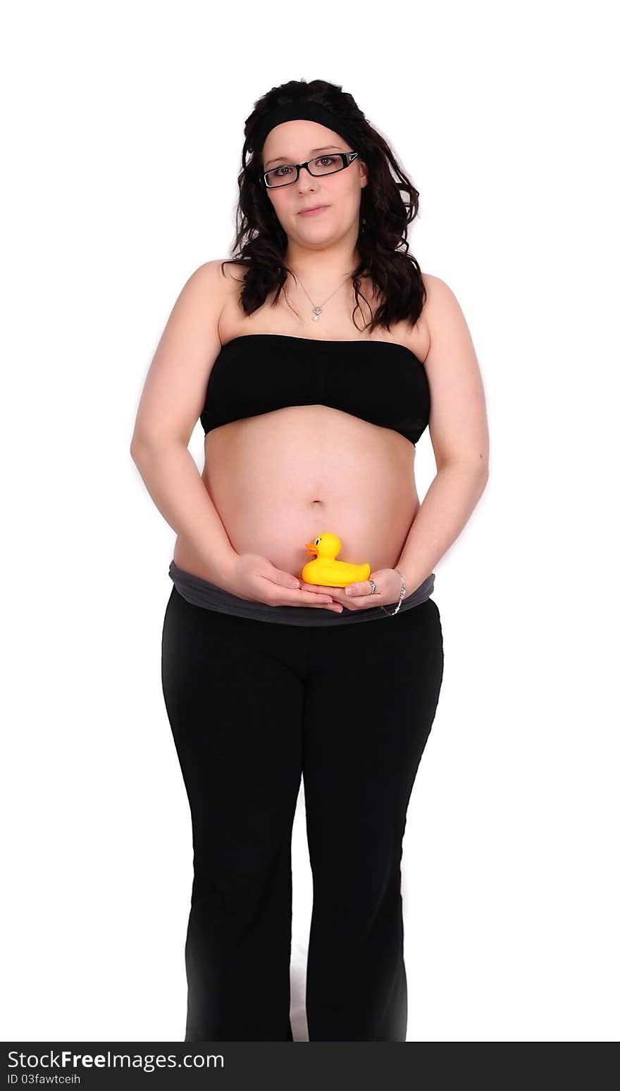 Beautiful pregnant woman standing holding a colourful small toy duck by her bare belly. Beautiful pregnant woman standing holding a colourful small toy duck by her bare belly