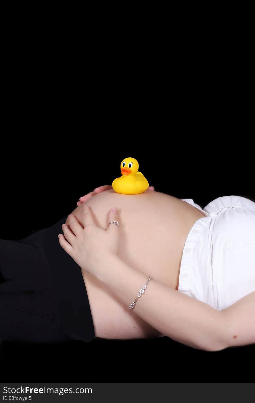 Colourful toy duck resting atop a pregnant belly