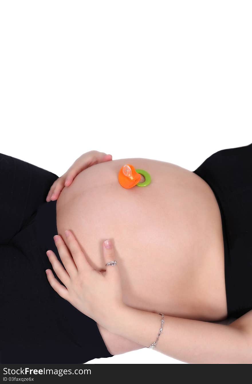 Colourful pacifier resting on top of a bare pregnant belly. woman with hands on belly. isolated on white. Colourful pacifier resting on top of a bare pregnant belly. woman with hands on belly. isolated on white.