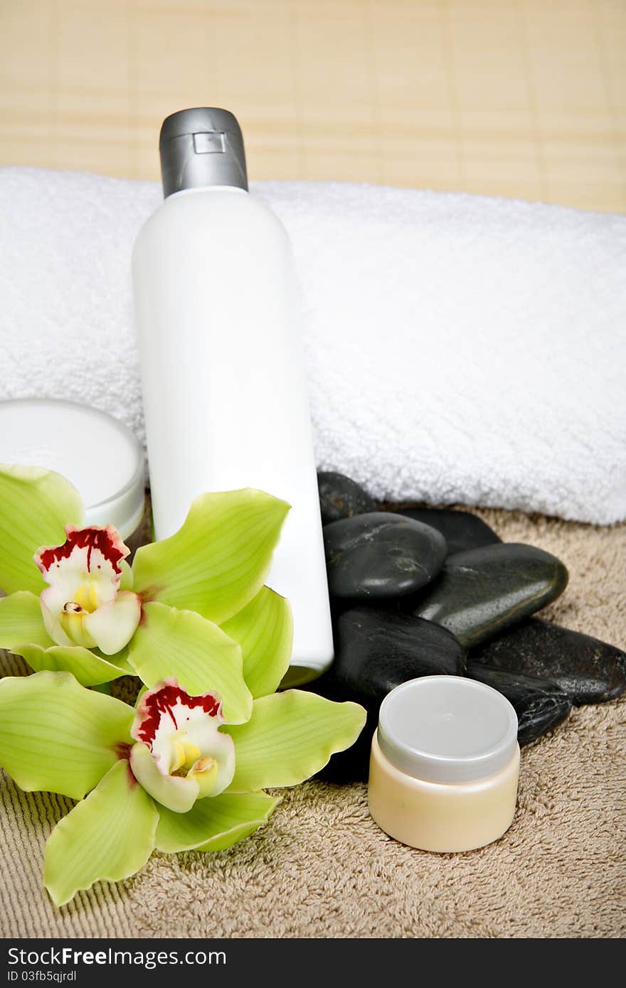 Different spa products: cosmetics, massage stones, towels, orchids. Different spa products: cosmetics, massage stones, towels, orchids