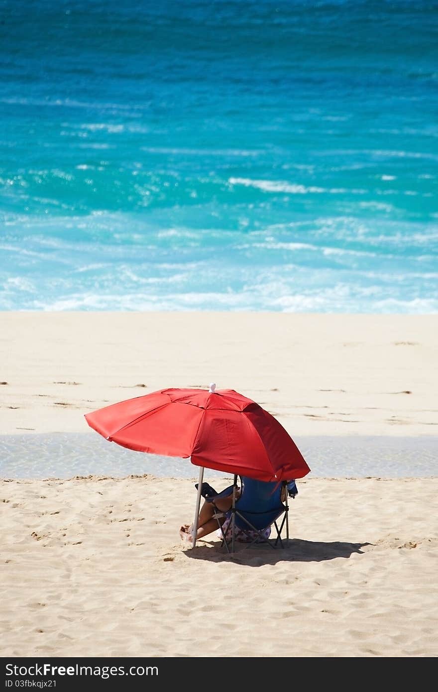 Beach Scene with Red Umbrella and Blue Water