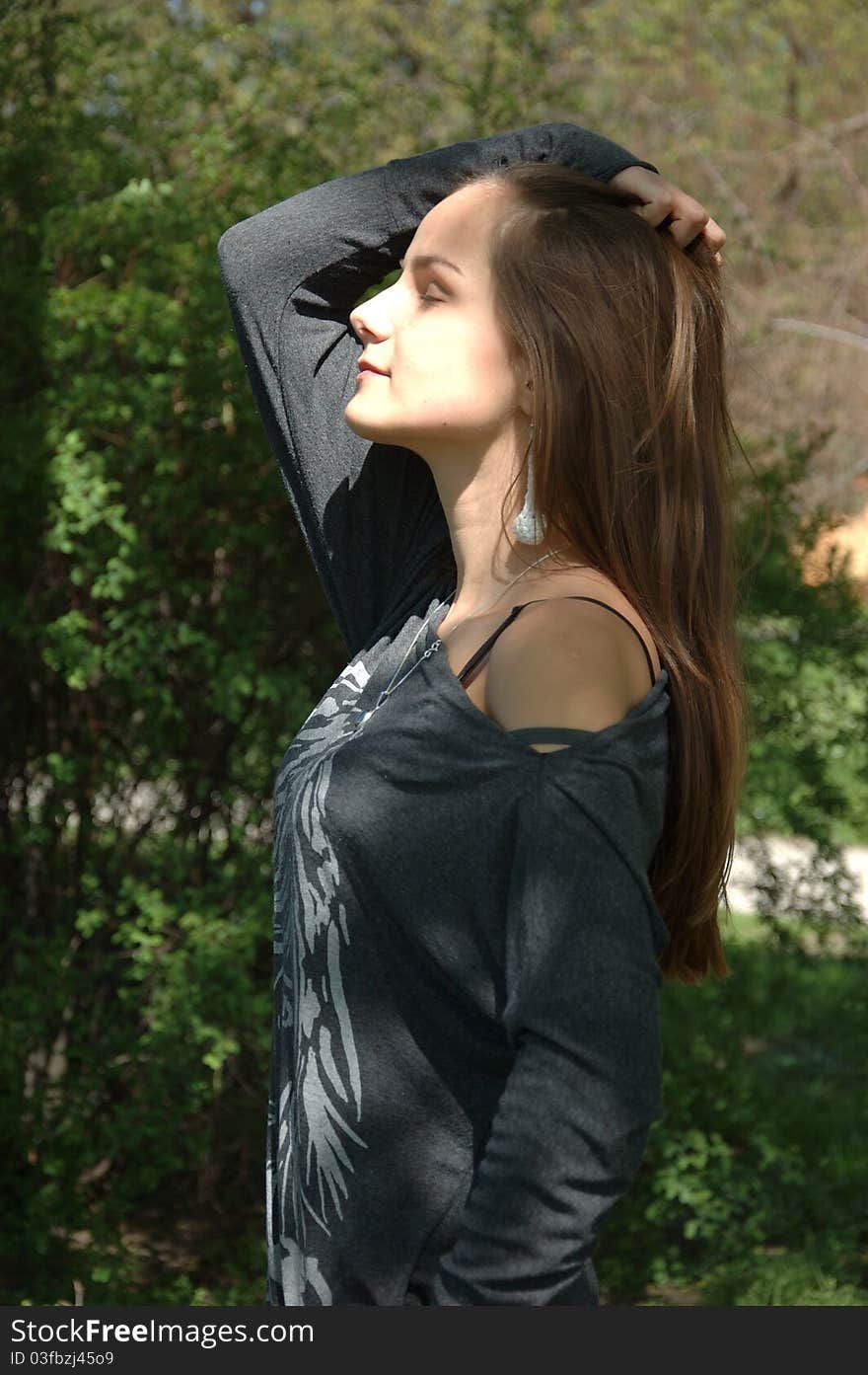 Girl dreaming in park. Teenager with her eyes closed, posing for photo in park with green trees as background. Girl dreaming in park. Teenager with her eyes closed, posing for photo in park with green trees as background.