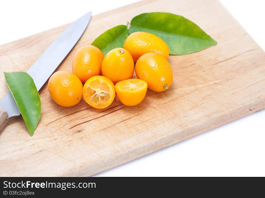 Kumquat on breadboard with knife and green leaves