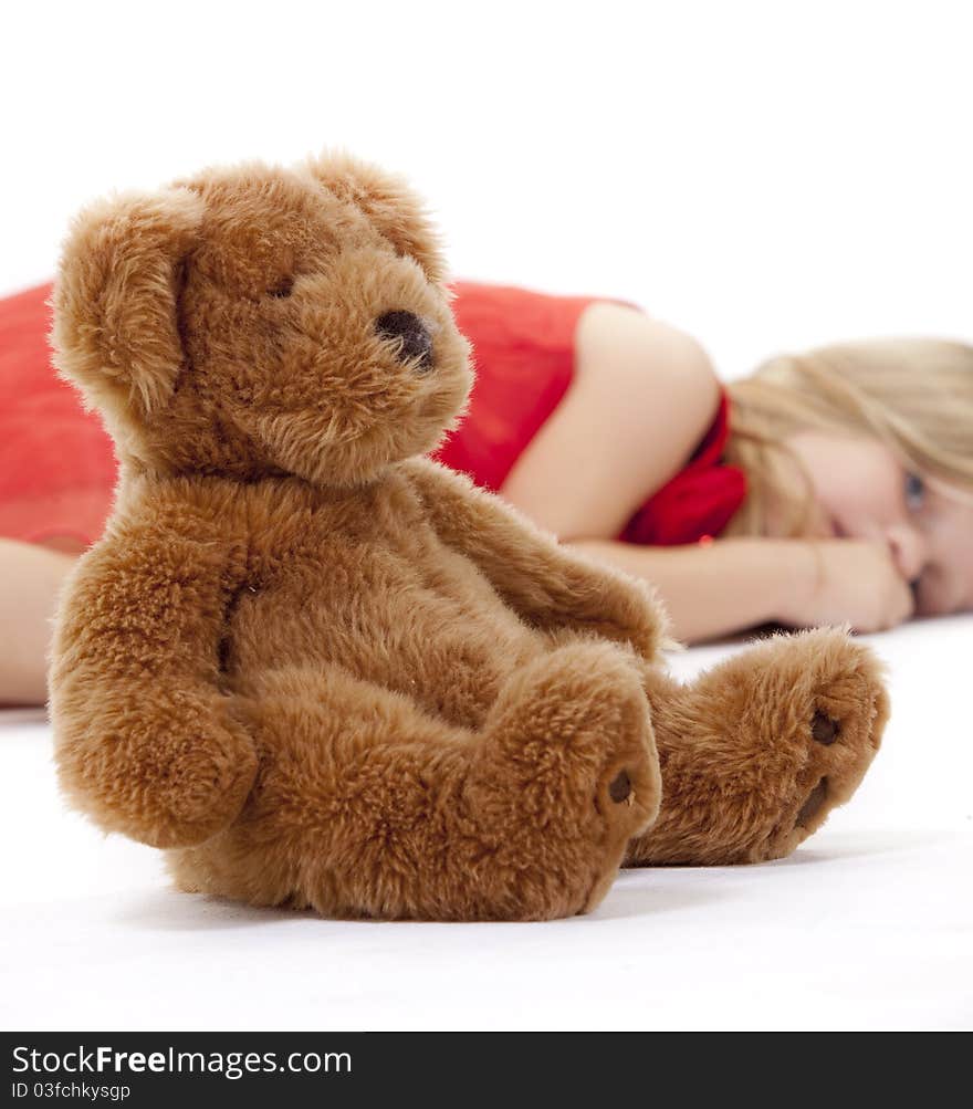 Little girl lying on floor in a red dress with her teddy bear infront of her. Little girl lying on floor in a red dress with her teddy bear infront of her.