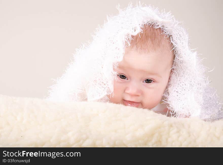 Infant covered by textile peeps out through some blanket