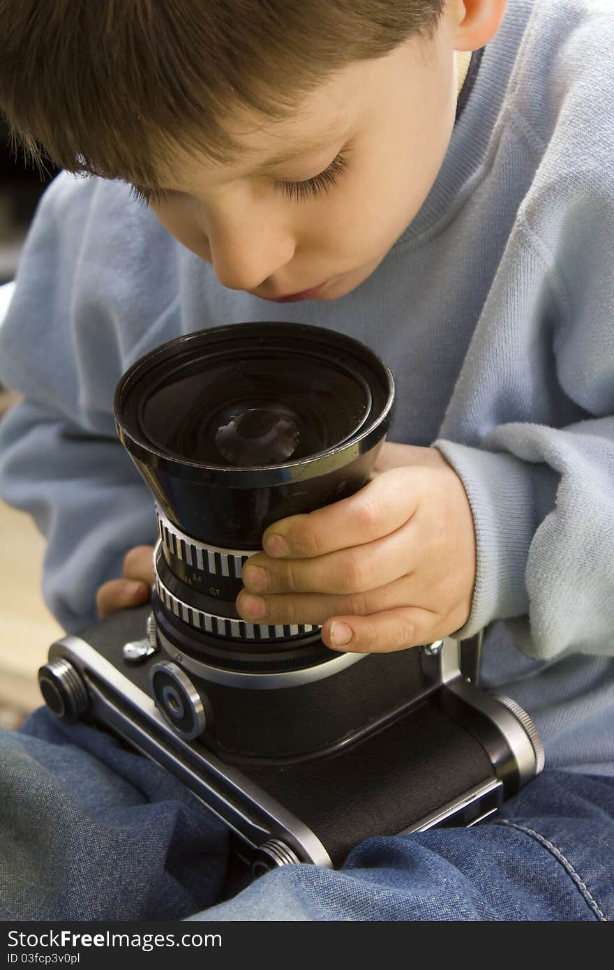 Young boy examining a vintage medium format camera. Young boy examining a vintage medium format camera