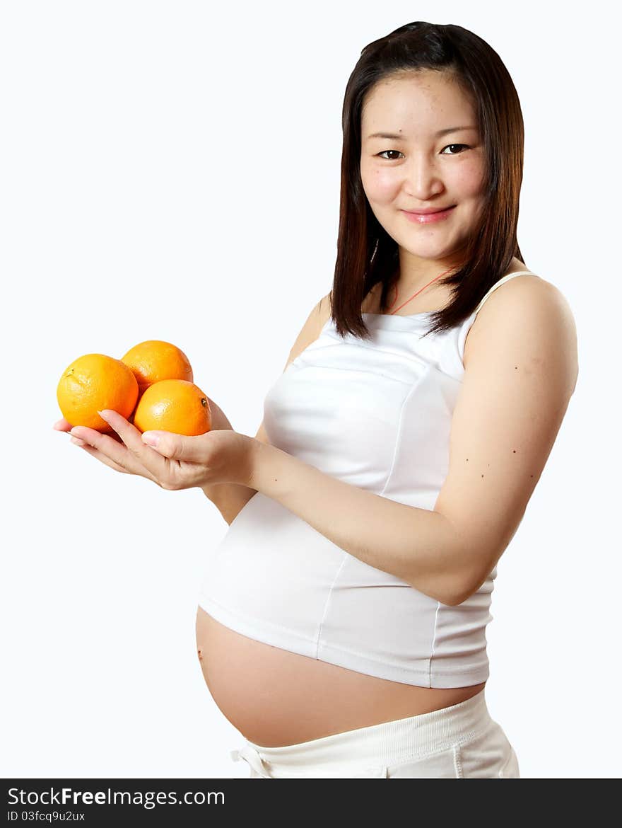 A young pregnant Asian woman with oranges for a healthy snack