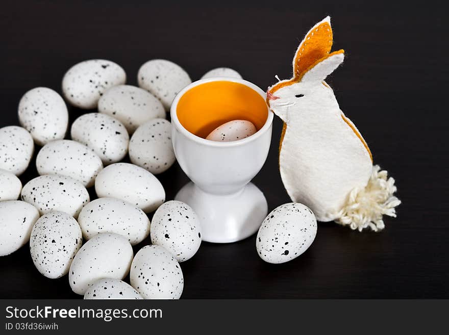 Quail eggs and handmade bunny on black background. Quail eggs and handmade bunny on black background