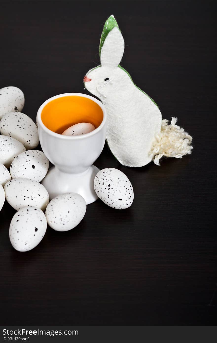 Quail eggs and handmade bunny on black background. Quail eggs and handmade bunny on black background