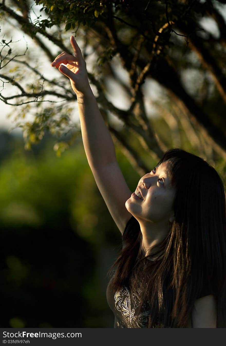 Girl under tree branches lookin up with smile. Girl under tree branches lookin up with smile