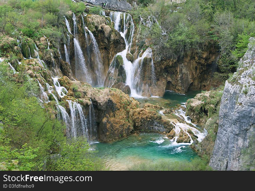 A beautiful waterfall running between greens lined with stones.