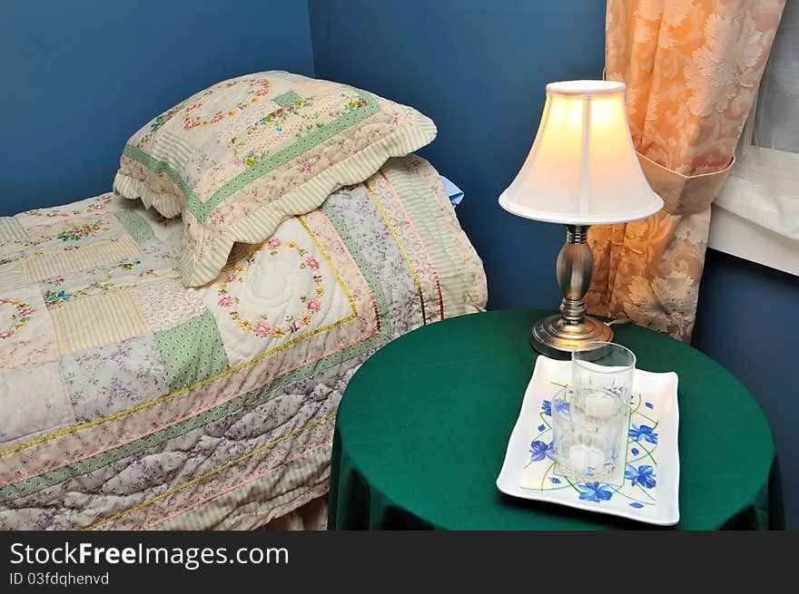 Clean drinking glasses on side table beside cozy bed. Clean drinking glasses on side table beside cozy bed.