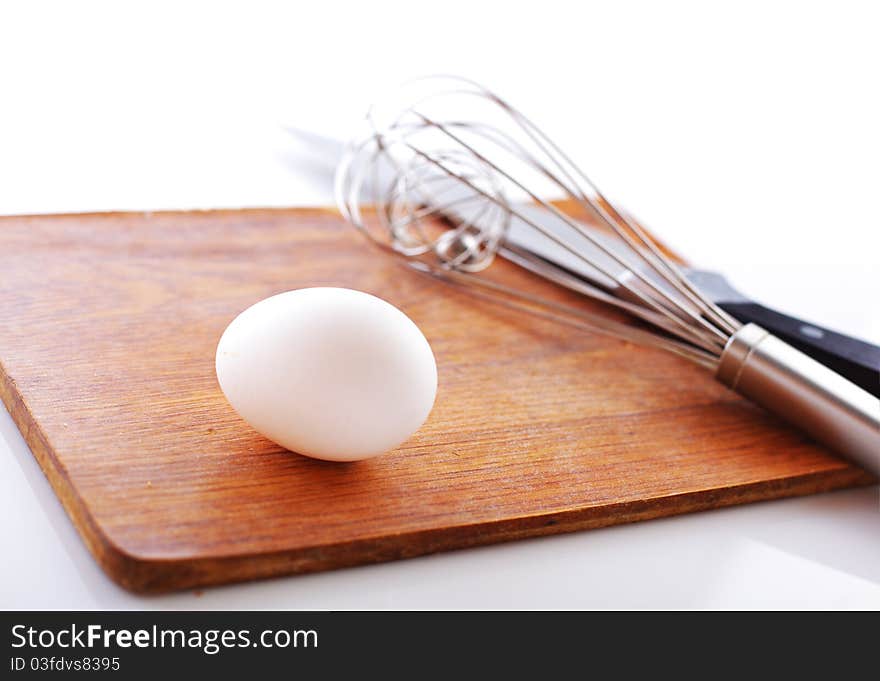 Eggs and whisk on white background