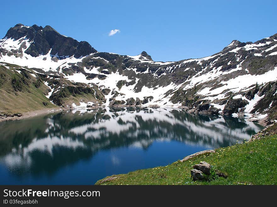 Mountain with snow is reflected in a mountain lake in the spring