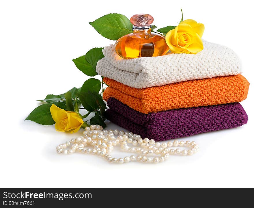 Yellow perfume bottle,roses and beads with towels on white background. Yellow perfume bottle,roses and beads with towels on white background