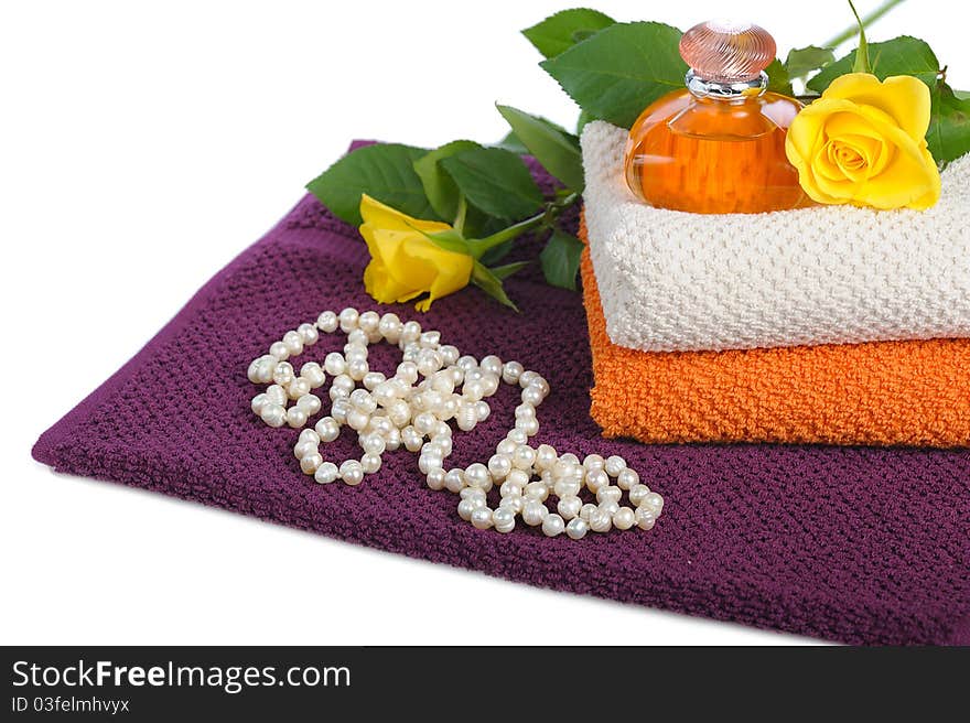 Yellow perfume bottle,roses and beads with towels on white background. Yellow perfume bottle,roses and beads with towels on white background