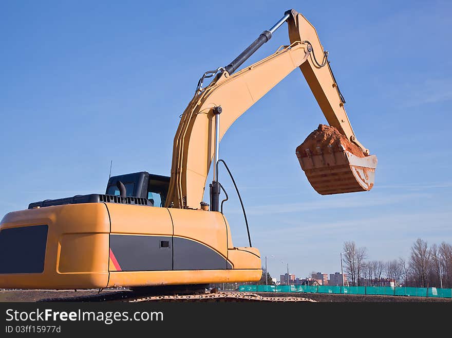 Excavator at construction site on a background of blue sky. Excavator at construction site on a background of blue sky