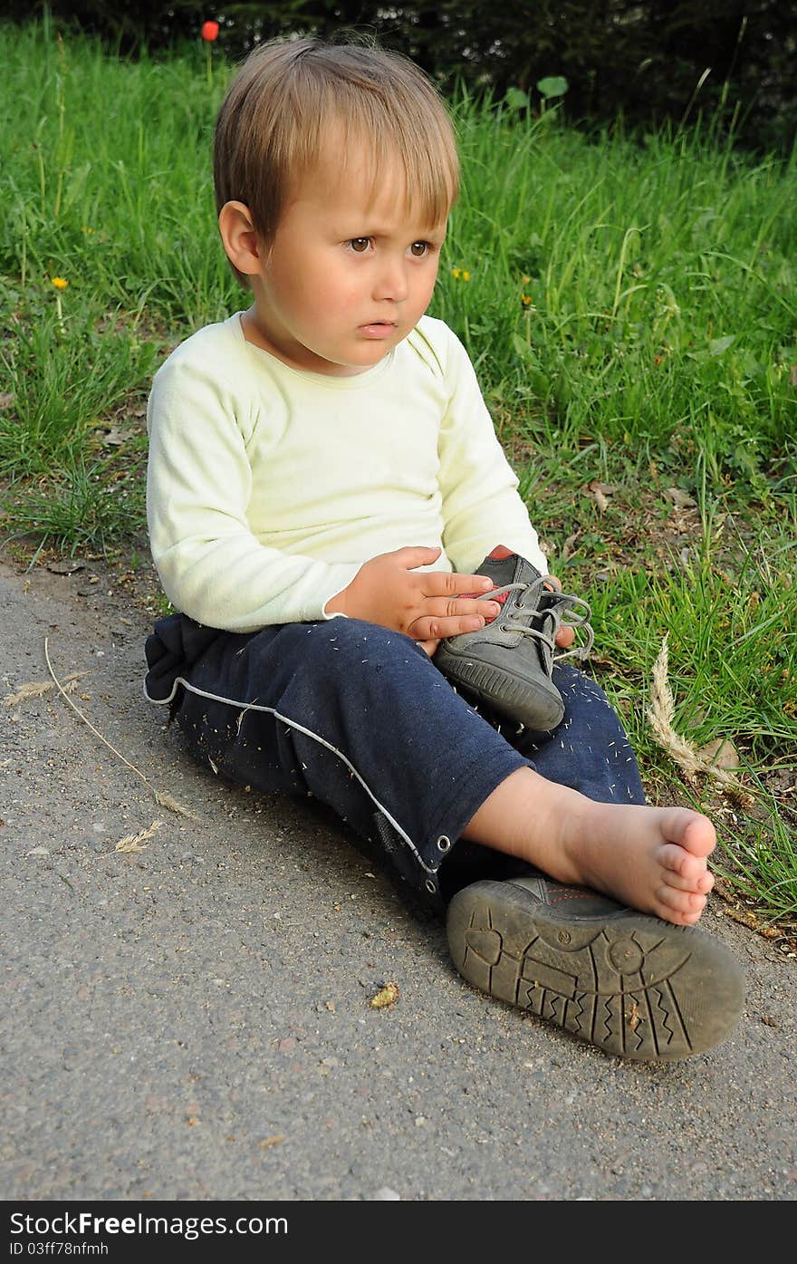 Young traveller, tired little child, sitting barefooted and having rest during travelling